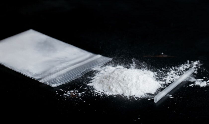 ketamine drugs and plastic straw on bag of white powder on black wood background.Drug epidemic concept.