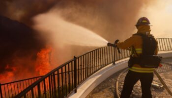 A firefighter makes a stand in front of the advancing Palisades Fire in the Pacific Palisades neighborhood of Los Angeles, Tuesday, Jan. 7, 2025. (AP Photo/Etienne Laurent)