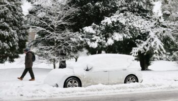 A man walks past a snow-covered car on a road in Buxton, Derbyshire, on 8 January 2025. Pic: Reuters