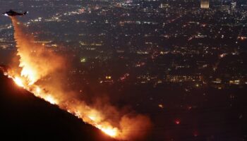 Un hélicoptère de lutte contre les incendies largue de l'eau alors que le Sunset Fire brûle dans les Hollywood Hills, à Los Angeles le 8 janvier 2025.