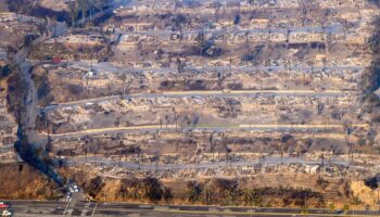 In this aerial view taken from a helicopter, burned homes are seen from above during the Palisades fire in Los Angeles county, California on January 9, 2025. Massive wildfires that engulfed whole neighborhoods and displaced thousands in Los Angeles remained totally uncontained January 9, 2025, authorities said, as US National Guard soldiers readied to hit the streets to help quell disorder. Swaths of the United States' second-largest city lay in ruins, with smoke blanketing the sky and an acrid smell pervading almost every building. (Photo by JOSH EDELSON / AFP)