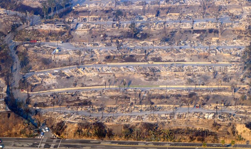 In this aerial view taken from a helicopter, burned homes are seen from above during the Palisades fire in Los Angeles county, California on January 9, 2025. Massive wildfires that engulfed whole neighborhoods and displaced thousands in Los Angeles remained totally uncontained January 9, 2025, authorities said, as US National Guard soldiers readied to hit the streets to help quell disorder. Swaths of the United States' second-largest city lay in ruins, with smoke blanketing the sky and an acrid smell pervading almost every building. (Photo by JOSH EDELSON / AFP)