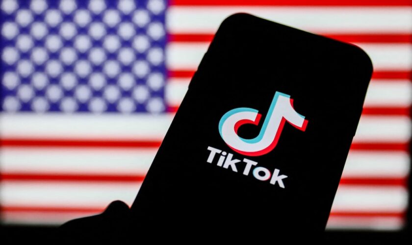 TikTok logo is seen displayed on a phone screen with American flag in the background in this illustration photo taken on August 2, 2020. President of the USA Donald Trump said that Chinese app TikTok will be banned in the United States. (Photo Illustration by Jakub Porzycki/NurPhoto) (Photo by Jakub Porzycki / NurPhoto / NurPhoto via AFP)