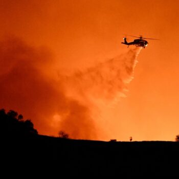 Un hélicoptère fait un largage sur des incendies en cours entre les quartiers de Mulholland drive et d'Encino, le 10 janvier 2025 à Los Angeles