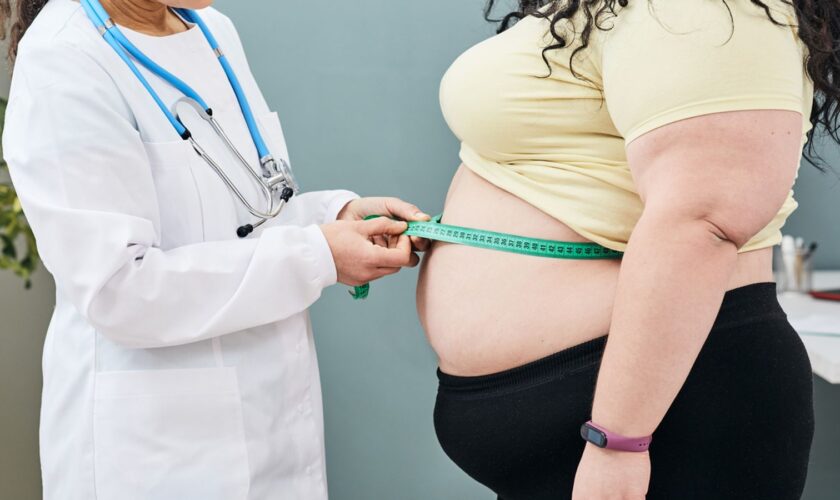 Obesity, unhealthy weight. Nutritionist inspecting a woman's waist using a meter tape to prescribe a weight loss diet