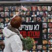 Une femme accroche une fleur sur un mur recouvert des portraits des otages israliens détenus dans la bande de Gaza, le 12 février 2024 à Jérusalem