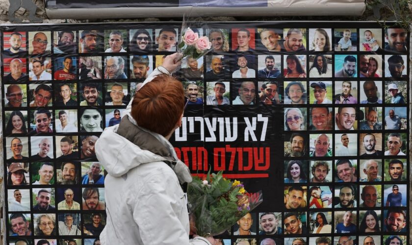 Une femme accroche une fleur sur un mur recouvert des portraits des otages israliens détenus dans la bande de Gaza, le 12 février 2024 à Jérusalem