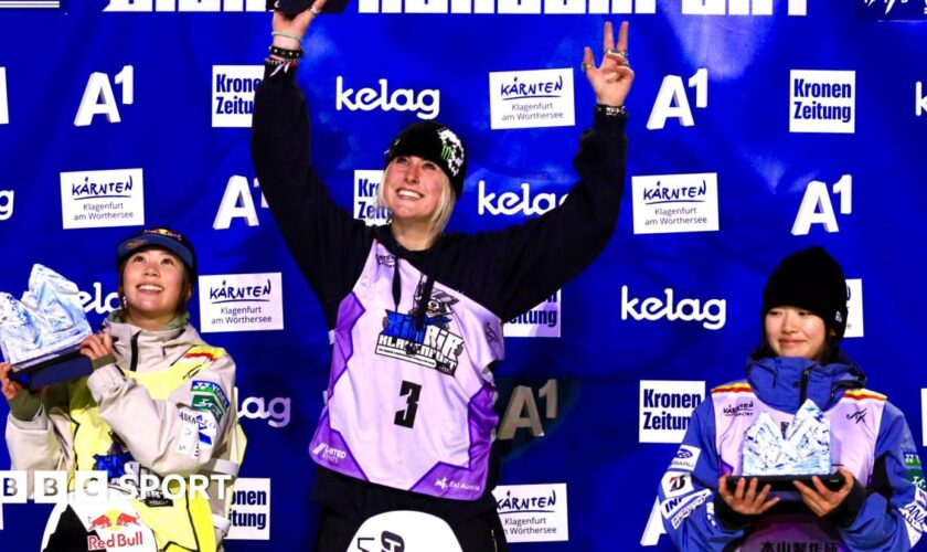 Mia Brookes lifts her trophy on the podium after winning the big air World Cup event in Klagenfurt