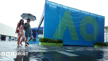 Fans arrive at Melbourne Park under an umbrella