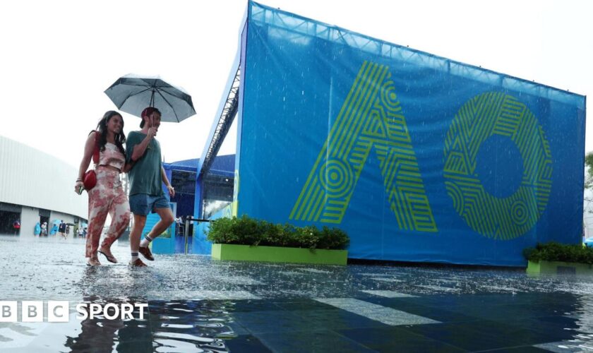 Fans arrive at Melbourne Park under an umbrella