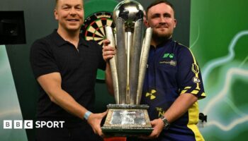 Luke Littler holding the Sid Waddell trophy alongside Sir Chris Hoy