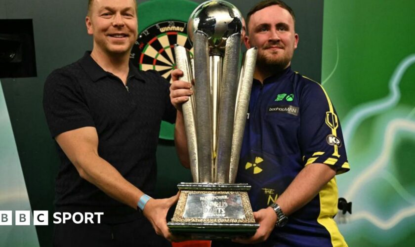 Luke Littler holding the Sid Waddell trophy alongside Sir Chris Hoy