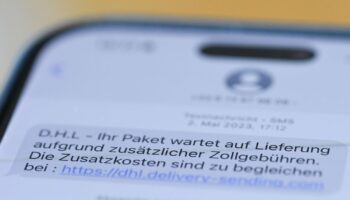 Auf einem Smartphone ist eine Betrugs-SMS zu lesen, in der Kriminelle ein Paket ankündigen und dafür Zollgebühren einfordern. Fo