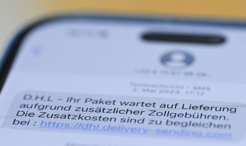 Auf einem Smartphone ist eine Betrugs-SMS zu lesen, in der Kriminelle ein Paket ankündigen und dafür Zollgebühren einfordern. Fo